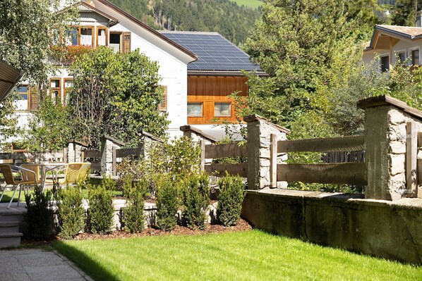 A residential building with a solar panel roof, a wooden deck, and a stone wall. - Premium Apartment Hofer Barbara – Fast Internet, Free Parking (Niederdorf)