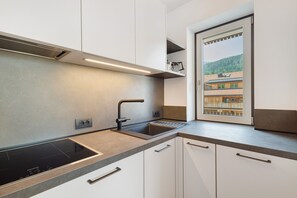 A modern kitchen with a built-in stove, a sink, and a window with a view of a building.