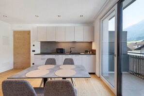 A modern kitchen with a microwave, cabinets, and a dining area with a table and chairs.