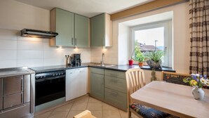 Una cocina compacta con estufa, lavamanos y gabinetes verdes.