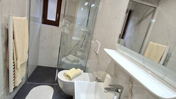 Une salle de bain moderne avec une douche en verre, un lavabo blanc et un sol carrelé en marbre.