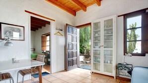 A kitchen with a dining table, chairs, a hanging light fixture, and a cabinet with glass doors. - Holiday Home Casa Consultorio with Mountain View, Pool, Wi-Fi & Terrace (GUATIZA)