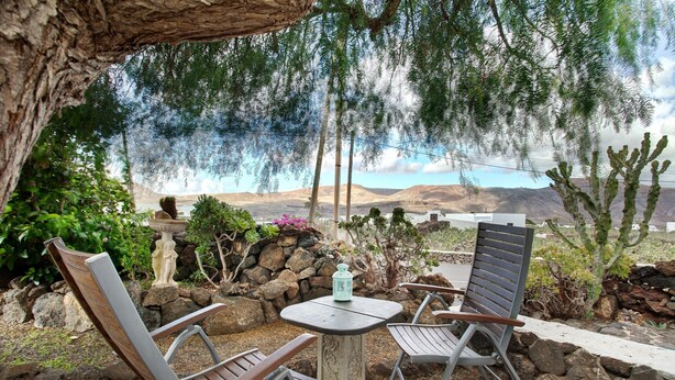 A patio with two chairs, a table, and a lantern. - Holiday Home Casa Consultorio with Mountain View, Pool, Wi-Fi & Terrace (GUATIZA)