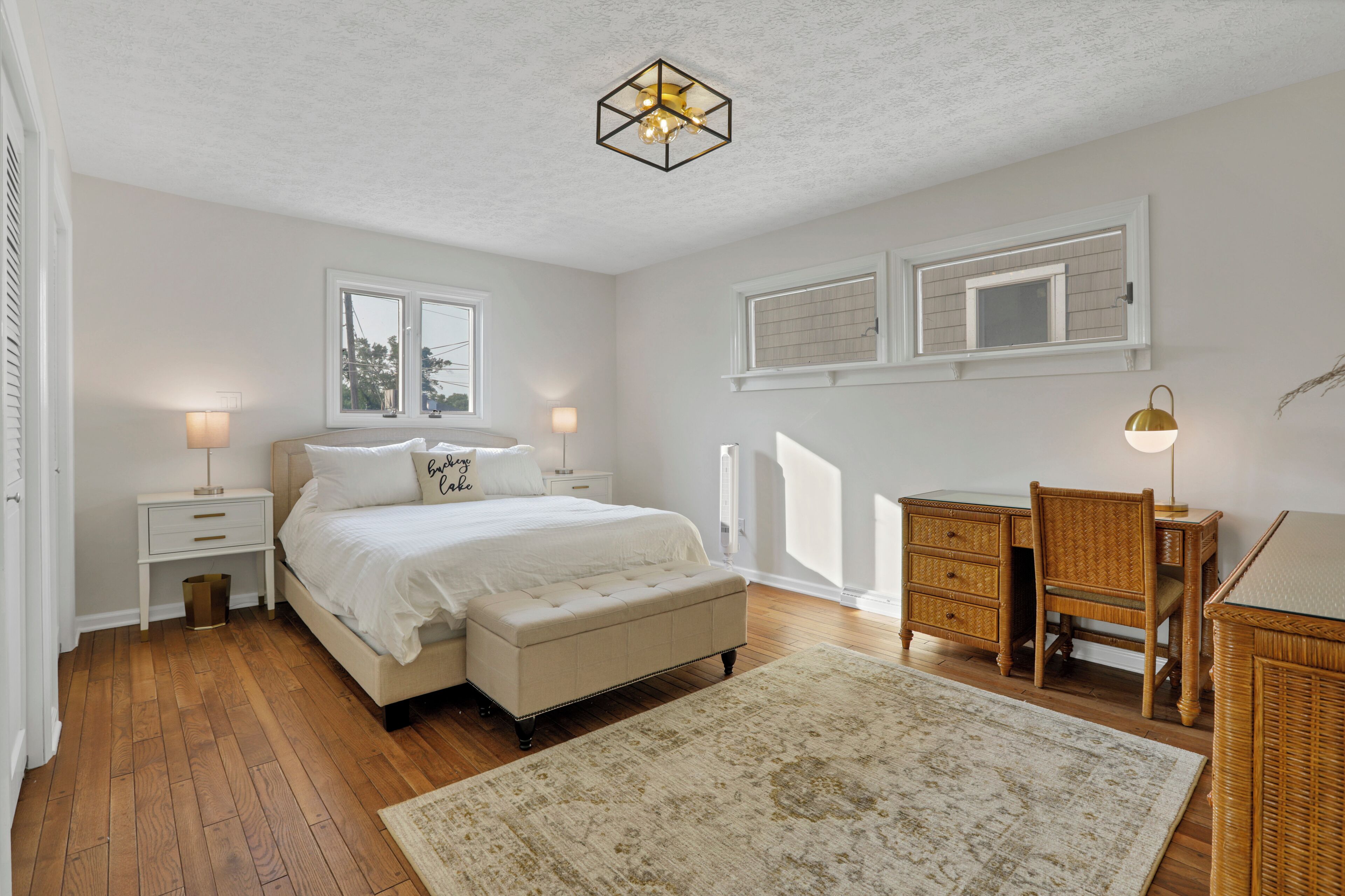 A bedroom with a bed, bedside tables, a desk, and a chair.