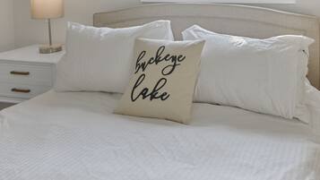 A neatly made bed with white linens and a pillow with text.