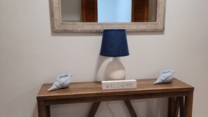 Une console en bois surmontée d’une lampe blanche et d’une pancarte de bienvenue.