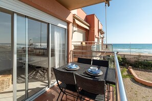 Un balcon avec une table et des chaises, donnant sur une plage.