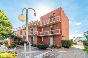 Un immeuble à plusieurs étages doté de balcons, d’un lampadaire et d’une cour recouverte de gravier.