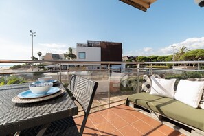 Un balcon avec une table, des chaises et un coin salon agrémenté de coussins.