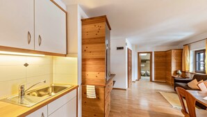 A modern kitchen with a stainless steel sink, wooden cabinets, and a wooden accent wall. - Holiday Apartment "Florerhof Lavendel" with Mountain View, Sauna, Wi-Fi & Garden (Völs am Schlern)