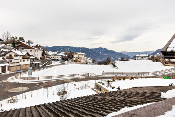 Un barrio residencial con casas, un paisaje nevado y montañas al fondo.