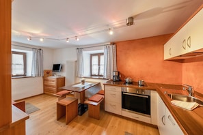 A compact kitchen with wooden countertops, a built-in oven, and a dining area with a bench.