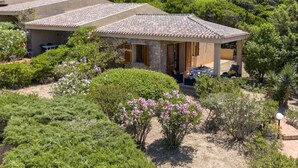 Una villa con techo de tejas, rodeada de exuberante follaje y plantas en flor.