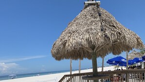 A beachside patio with a thatched umbrella, wooden deck, and turquoise stools. - Our house at the beach Most see<br>At siesta key  (Siesta Key)