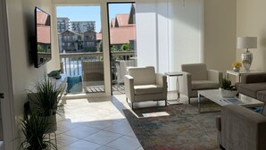 A spacious living room with a ceiling fan, a large window, and a view of buildings outside. - Our house at the beach Most see<br>At siesta key  (Siesta Key)