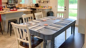 Una cocina moderna con una isla central, sillas blancas y una mesa de comedor con manteles individuales.