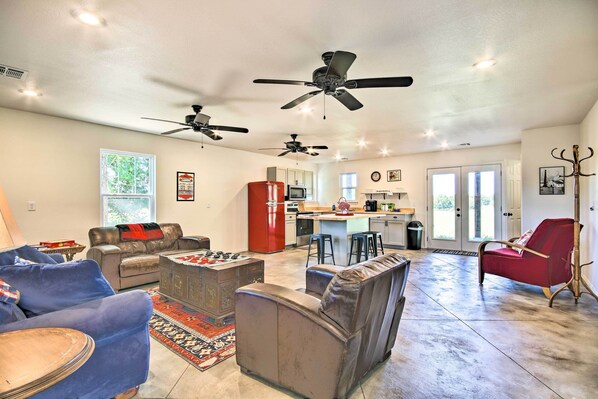 A spacious living area with a kitchen, two ceiling fans, a red refrigerator, and a red chair.