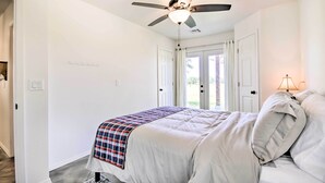 Un dormitorio con cama, ventilador de techo y puerta que da a un balcón.