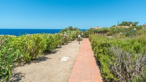 A paved pathway leading to a building with a view of the ocean. - Vacation home Cisto by Interhome (Costa Paradiso)