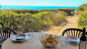 A table set for dining with a view of the ocean, a bottle of wine, and a basket of bread rolls. - Vacation home Cisto by Interhome (Costa Paradiso)