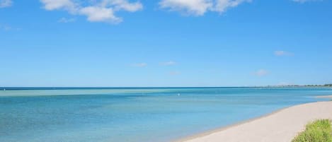 Una playa con agua azul cristalina y una orilla arenosa.