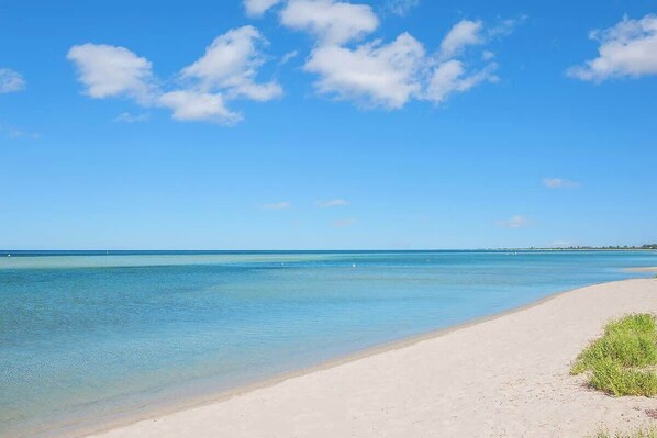 Une plage avec une eau d’un bleu limpide et un rivage sablonneux.