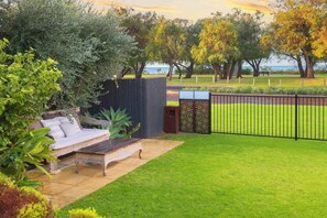 A well-maintained outdoor area with a seating area, a fenced garden, and a view of the sea.