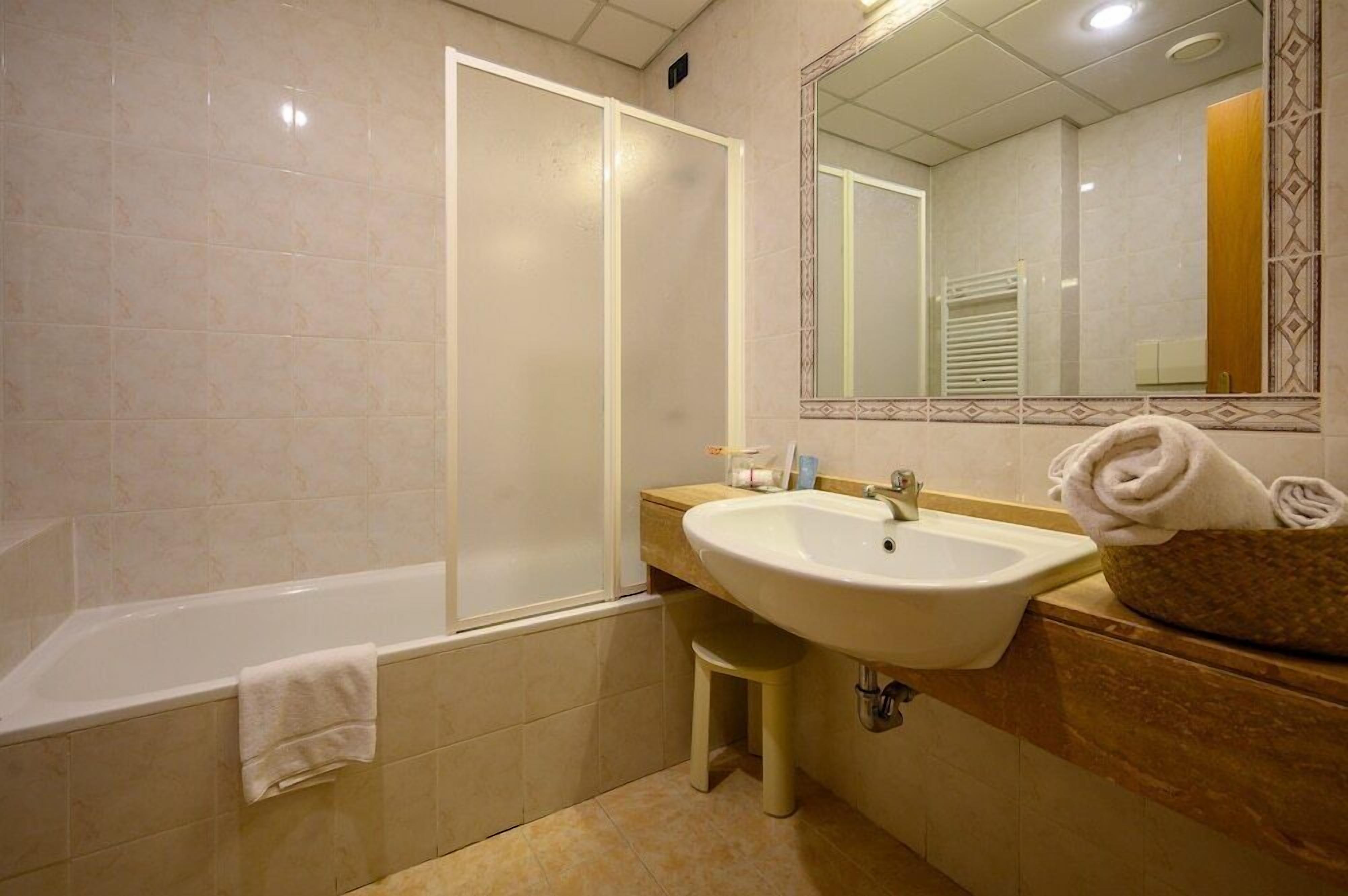 A bathroom with a bathtub, sink, and mirror.