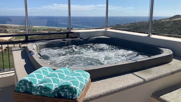 Een jacuzzi met uitzicht op de oceaan en heuvels op de achtergrond.