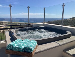 Un jacuzzi con vista despejada al océano y colinas al fondo.