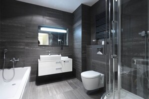 A modern bathroom with a glass-enclosed shower, a white sink, and a toilet.