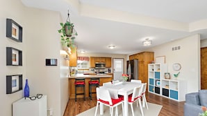 Una cucina moderna con mobili in legno, un'isola centrale e un'area pranzo con tavolo bianco e sedie rosse.