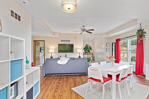 Relax in this stylish living room with a sofa, dining table, and mounted TV.