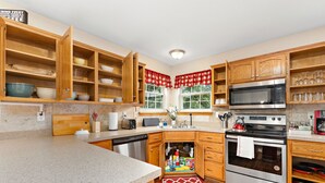 Una cucina con mobili in legno, un forno a microonde, un forno e uno scolapiatti.