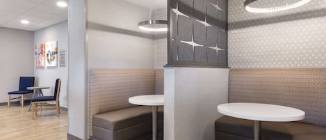 A modern interior with two round tables, cushioned seating, and contemporary wall designs.
