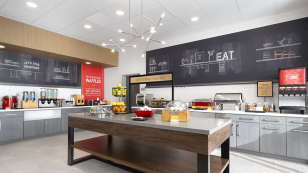 Une cuisine moderne dotée d’un îlot central, d’un bar pour prendre le petit-déjeuner et de divers appareils électroménagers.