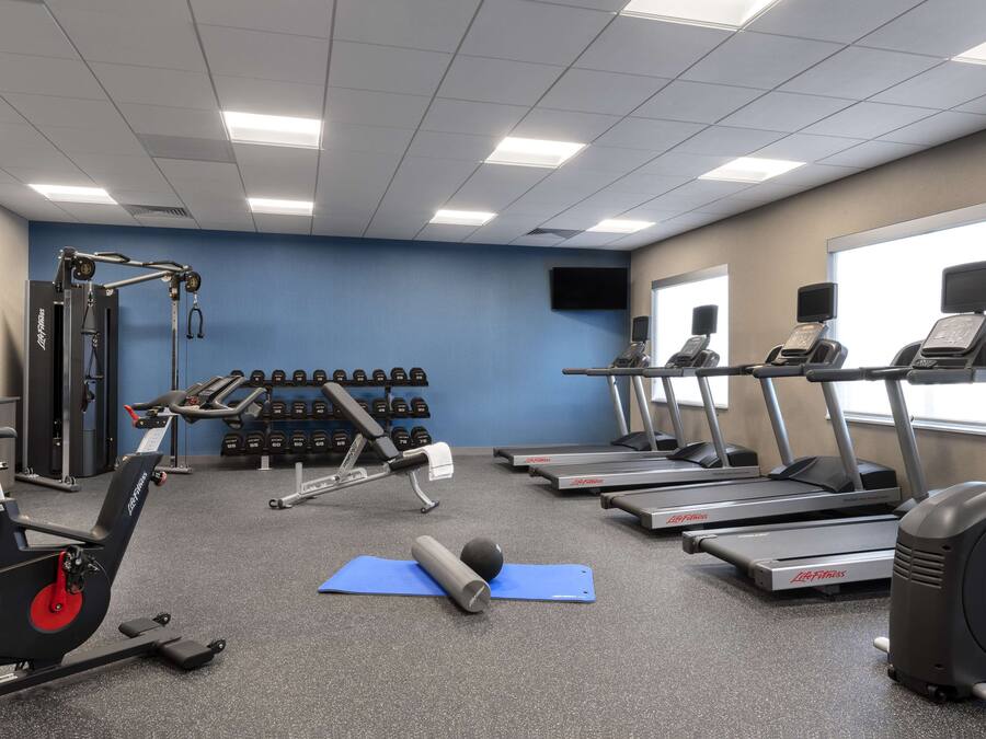 A gym with treadmills, an elliptical, free weights, and exercise mats.