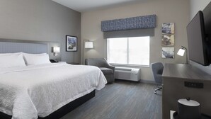 Une chambre d’hôtel avec un grand lit, un bureau, une chaise et une fenêtre donnant sur un beau paysage.