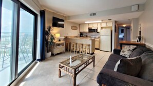 A modern apartment with a large living area, a kitchen, and a balcony with a city view.