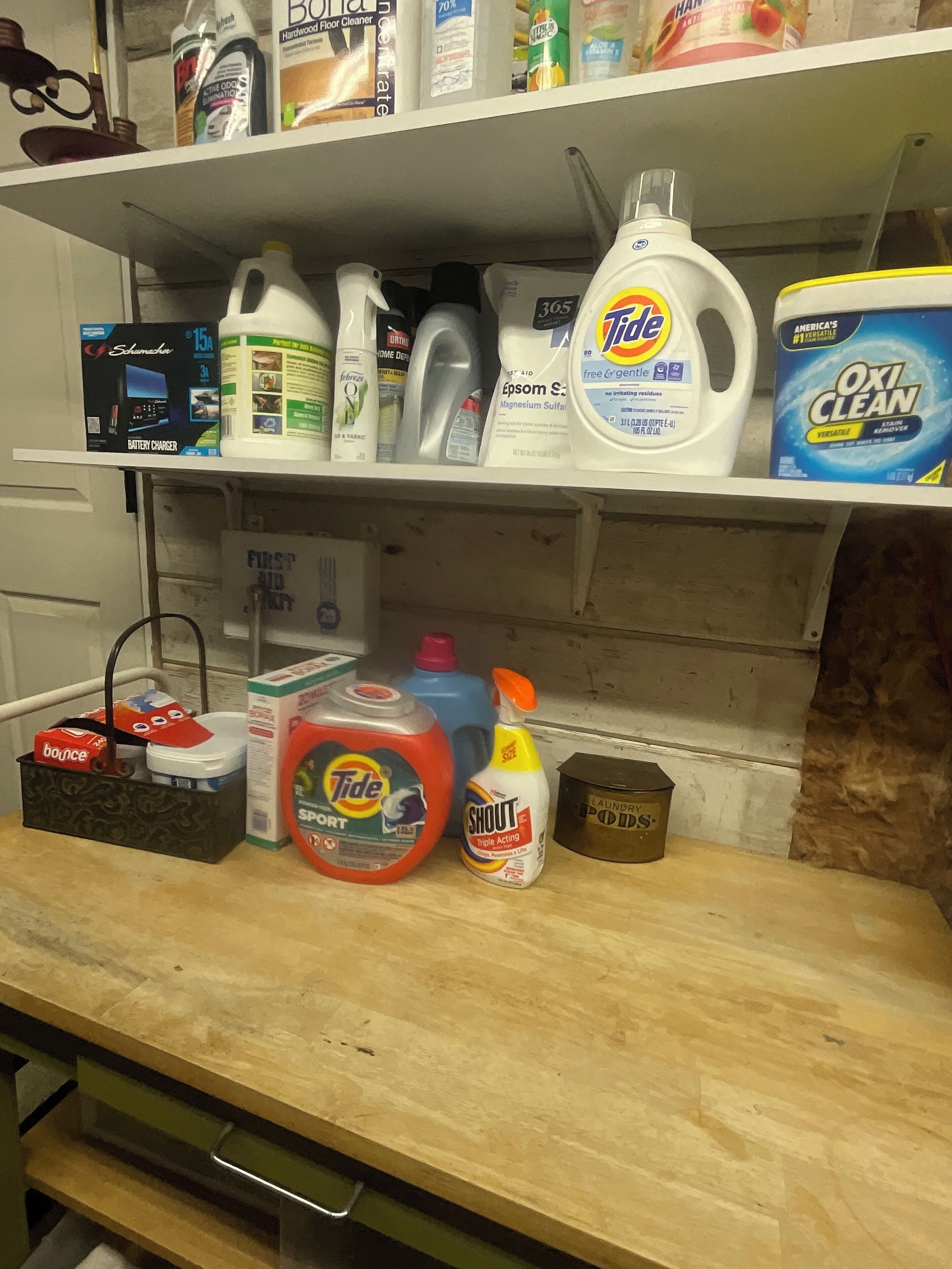 A shelf with various cleaning products and a battery charger.