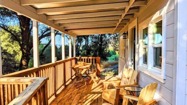 Eine Holzterrasse mit Sitzgelegenheiten und großen Fenstern.