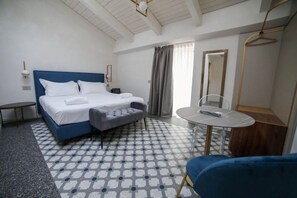 Une chambre d’hôtel avec un lit, une petite table, une chaise, un miroir et un porte-manteau mural.