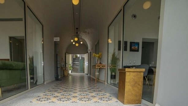 A hallway with a patterned floor, a wooden podium, and a staircase in the background.