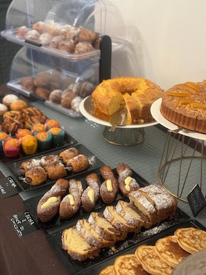 Verschiedene gebackene Köstlichkeiten auf Tabletts und Tellern, darunter Gebäck, Kuchen und Brot.