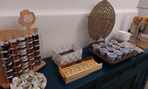 A food display with jars of preserves, a tray of yogurt, and a decorative wooden sign. - 20 Miglia Boutique Hotel (Catania)