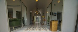 Um corredor com piso estampado, um púlpito de madeira e uma escadaria ao fundo.