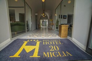 Eine Hotelhalle mit einem gemusterten Teppich, einem Empfangstresen und einer Treppe im Hintergrund.