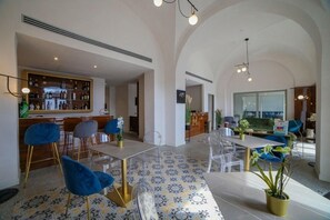 Un vaste espace dédié à la salle à manger, comprenant un bar, des chaises transparentes et un sol à motifs.