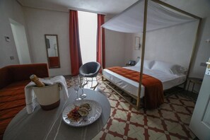 A hotel room with a bed, a chair, a table with a bottle and glasses, and a checkered floor. - 20 Miglia Boutique Hotel (Catania)