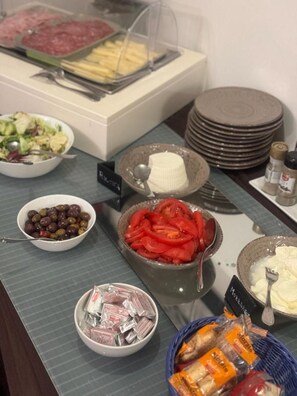 Un buffet proposant une variété de plats, notamment des olives, des tomates et du fromage.